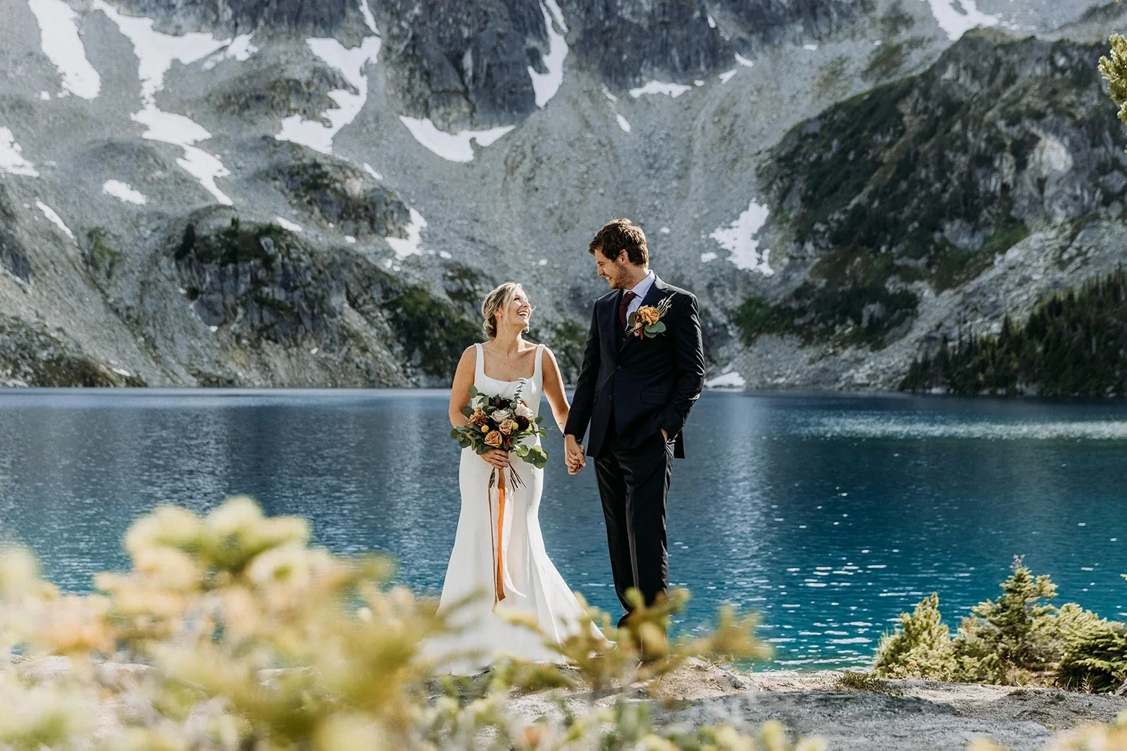 Bride and groom sharing smile beside water at Marriage Lake.