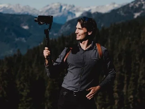 Person holding a camera on a gimbal in mountain landscape