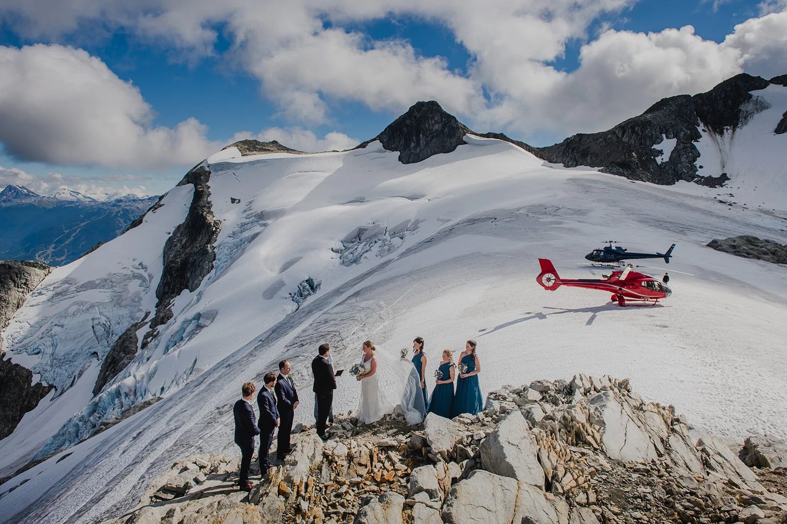 Bride and groom with family on winter mountain top during heli-wedding ceremony.