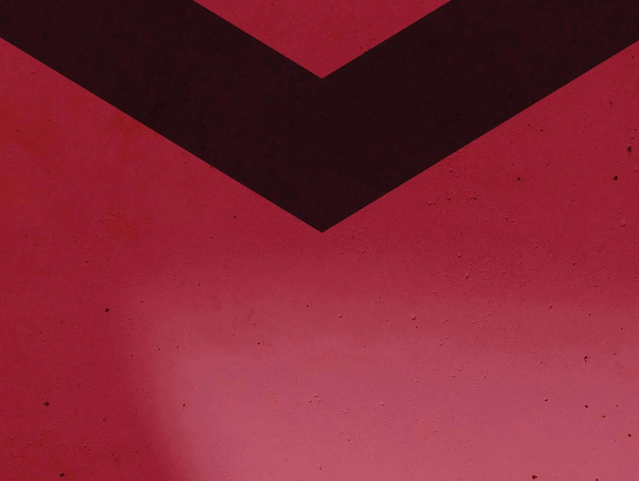 Close-up of a red surface with black geometric shapes forming an arrow or chevron pattern.