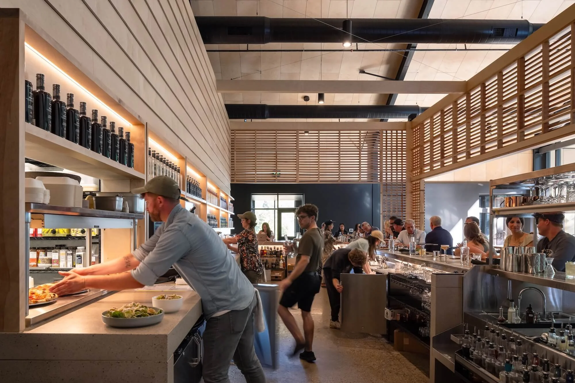People dining and ordering food at a modern restaurant with a bar and open kitchen.