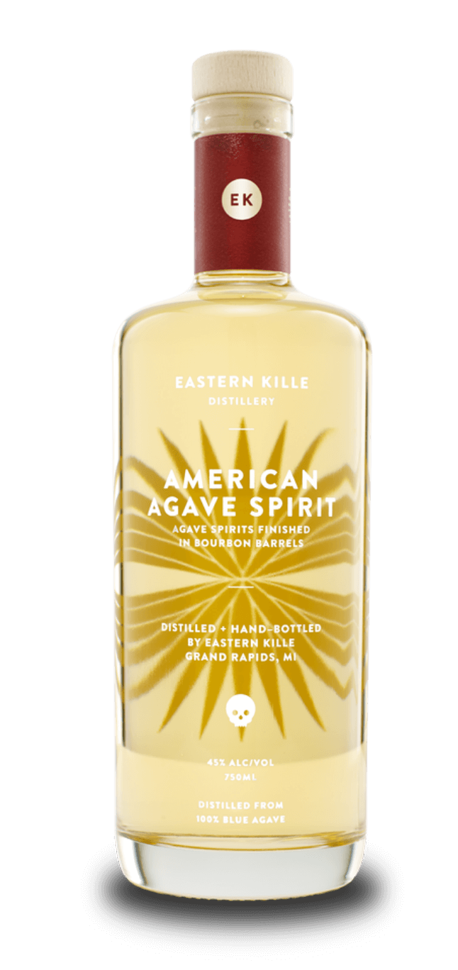 A bottle of Eastern Kille American Agave Spirit with a white cap and red neck label featuring a small circular logo with initials 'EK'. The clear glass bottle displays a light yellow liquid and has a yellow starburst design with a skull icon. The label states it is 45% alcohol by volume, 750ml, distilled from 100% blue agave in Grand Rapids, Michigan.