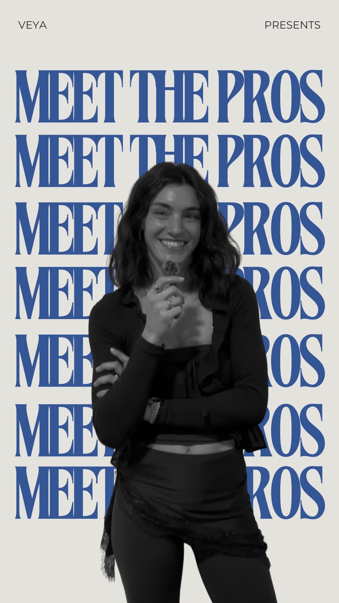 Woman smiling and holding a cookie with her right hand, standing in front of a background with blue text that says "Meet the Pros" repeated multiple times.