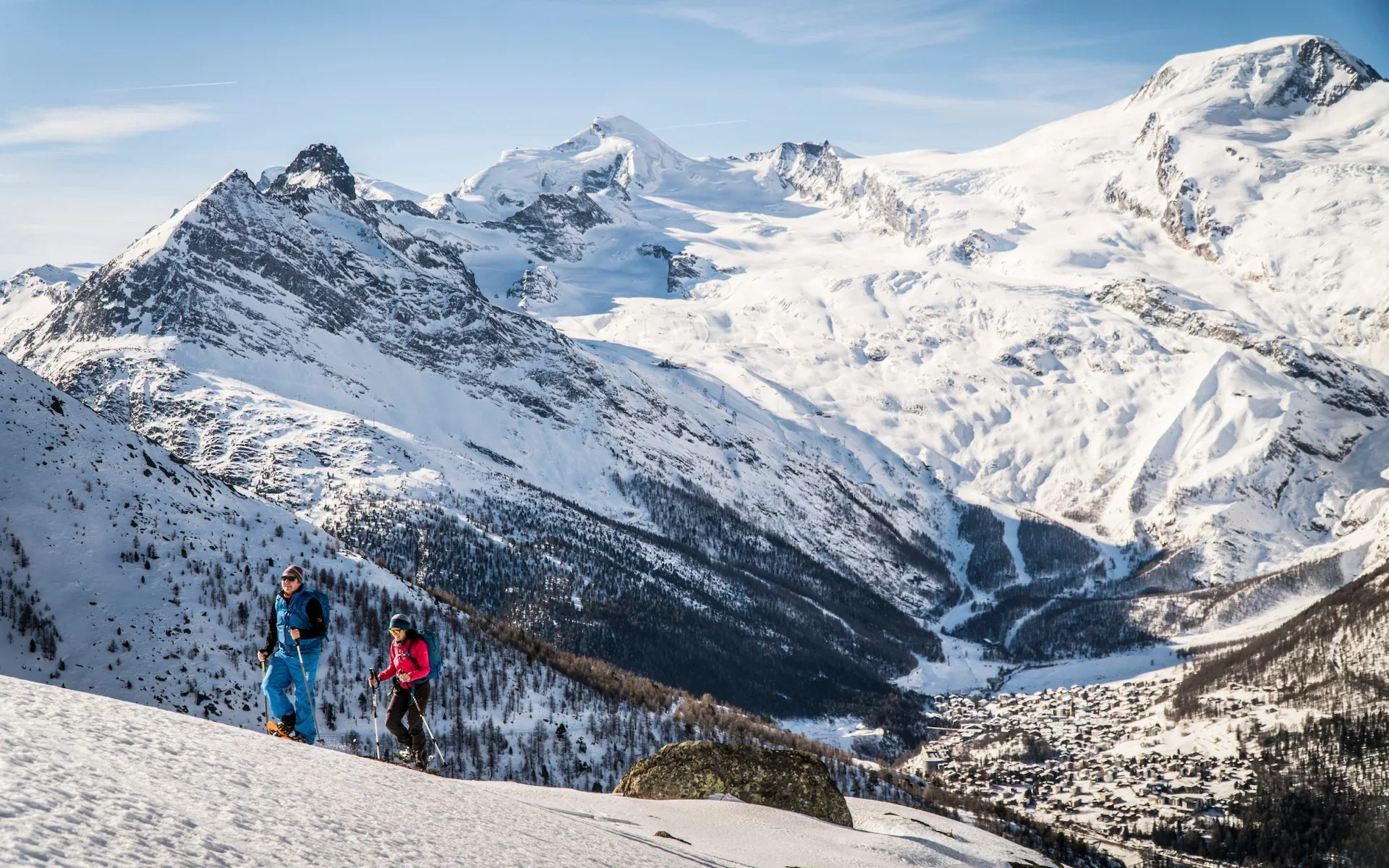 snowshoers and skigoers climbing snow capped mountain alpine peak