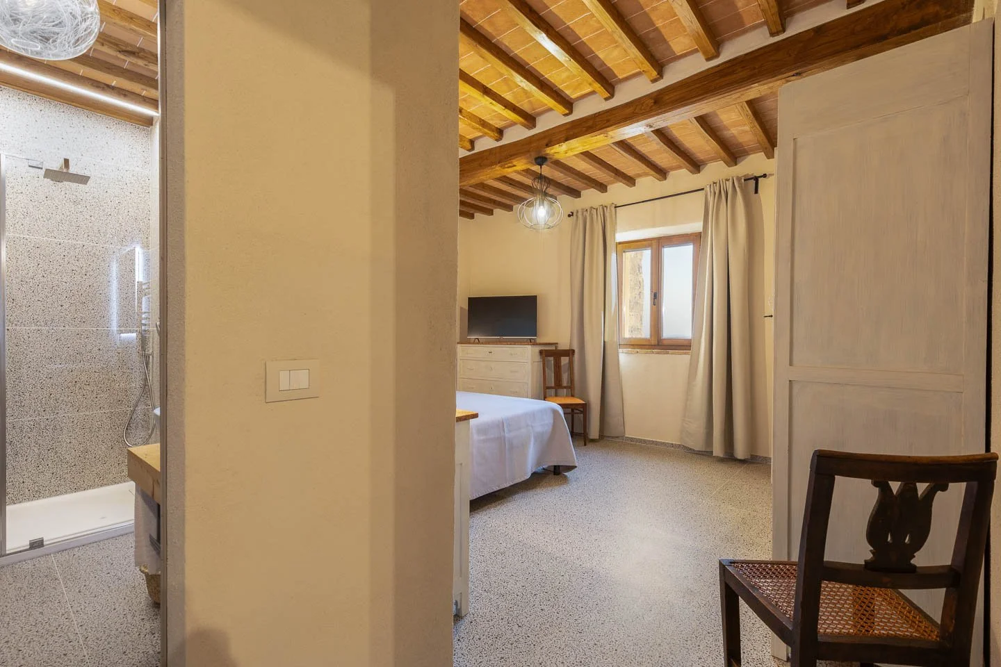 Bedroom with adjacent shower area in a luxury holiday apartment in San Gimignano historic center