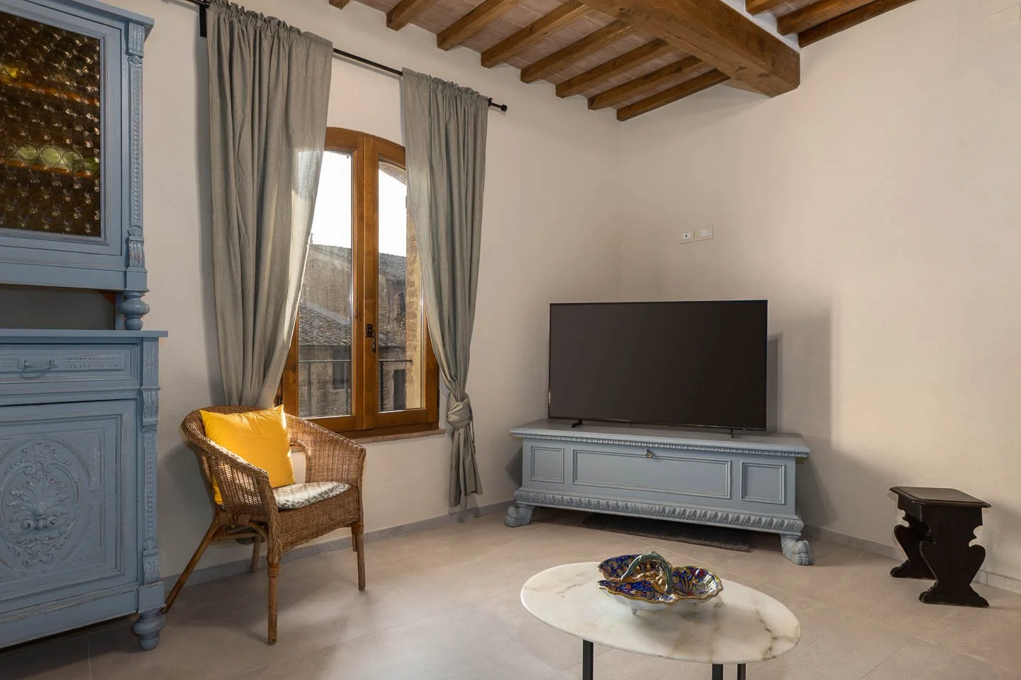 Living room with wooden beam ceiling in a high-end holiday apartment in the historic center of San Gimignano
