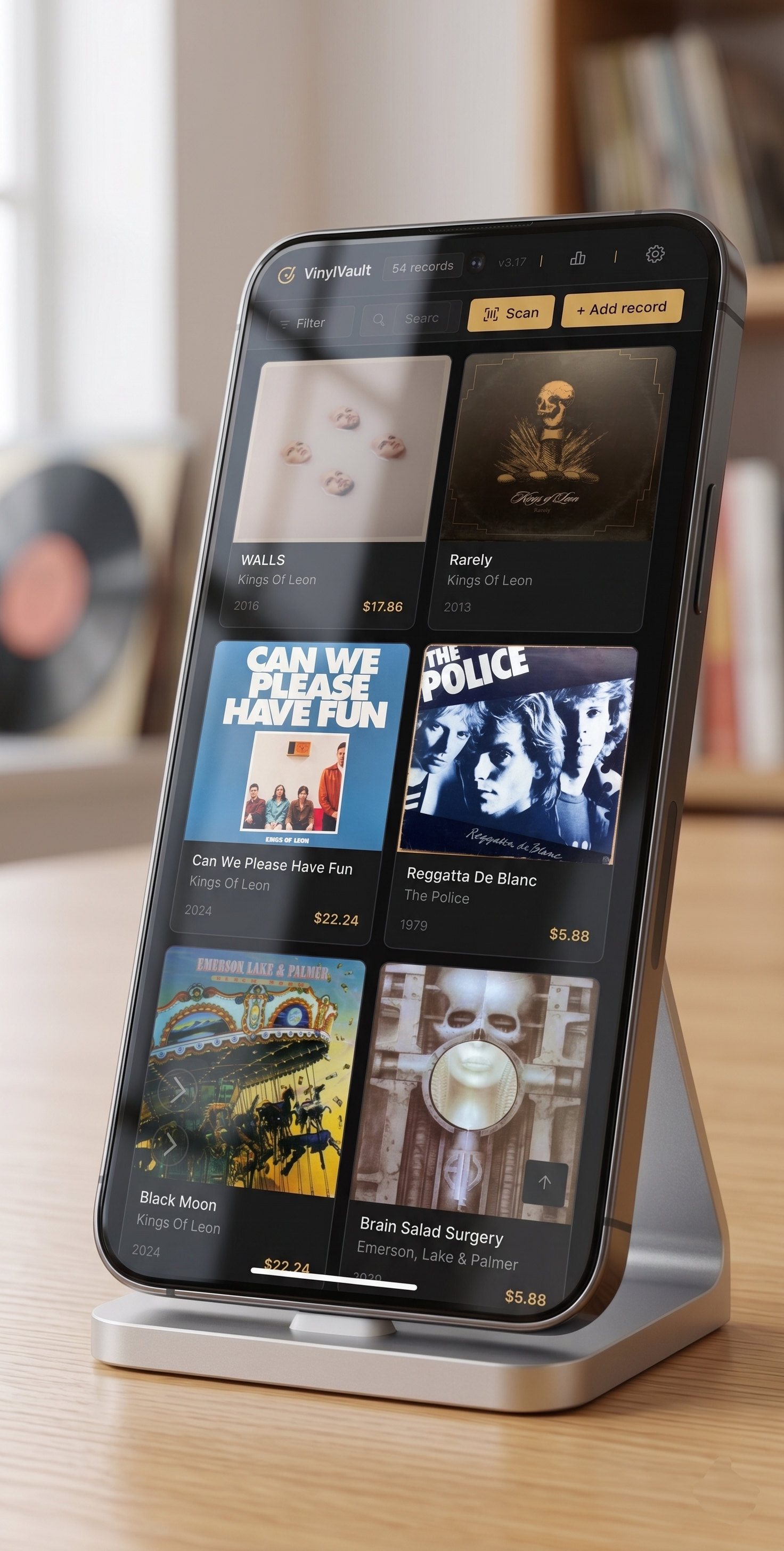 Smartphone displaying a music app with album covers and prices, placed on a wooden table.