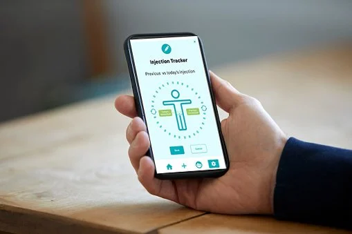 Person holding a smartphone displaying an infection tracker app with a syringe icon.