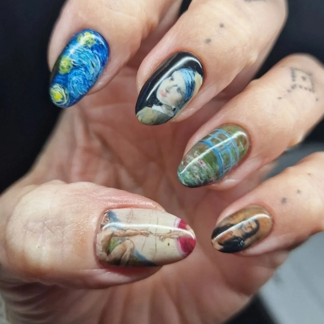 Close-up of a hand with five decorated nails featuring famous paintings by Van Gogh, Leonardo da Vinci, and others.