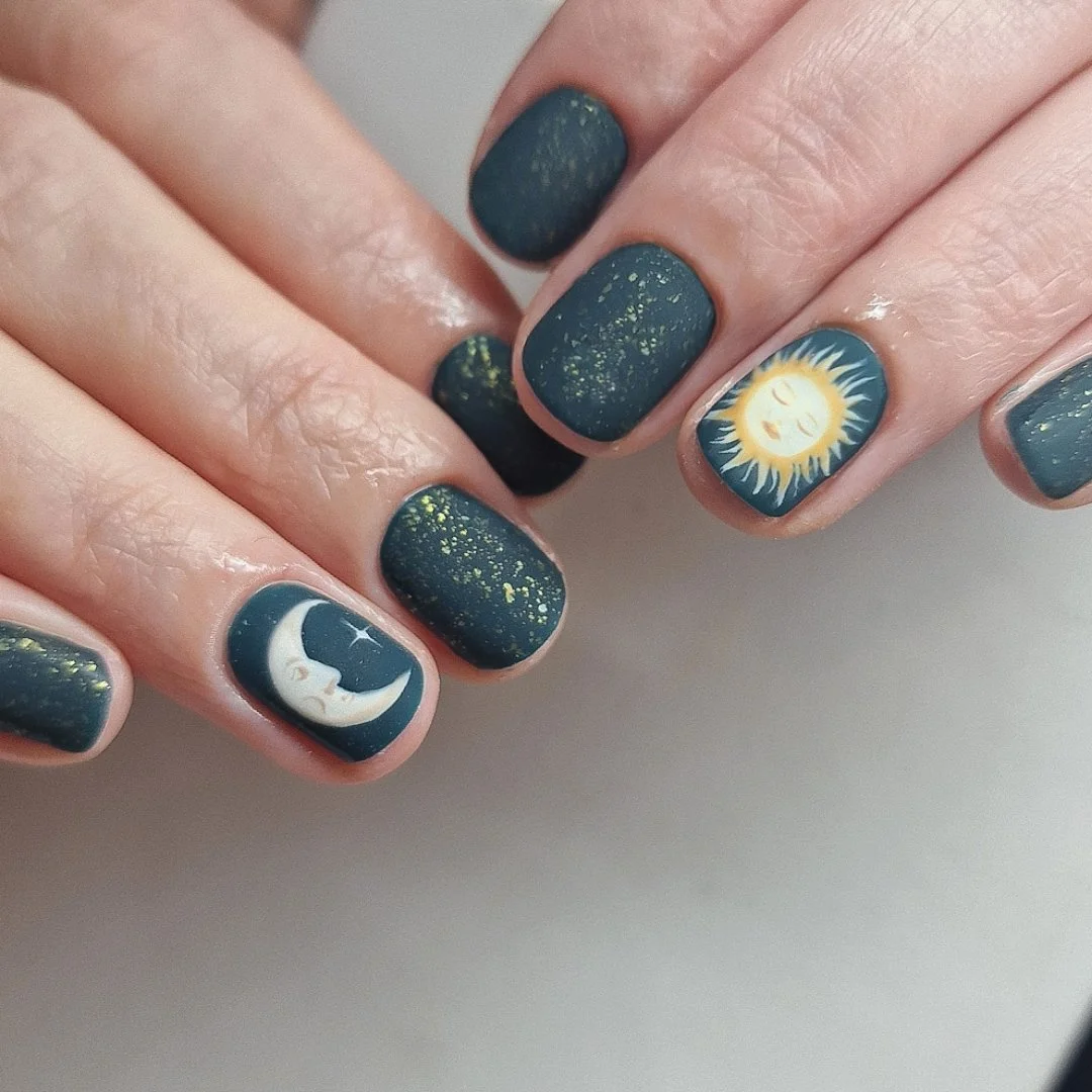 Nail art featuring moon and sun designs with dark green and gold accents.