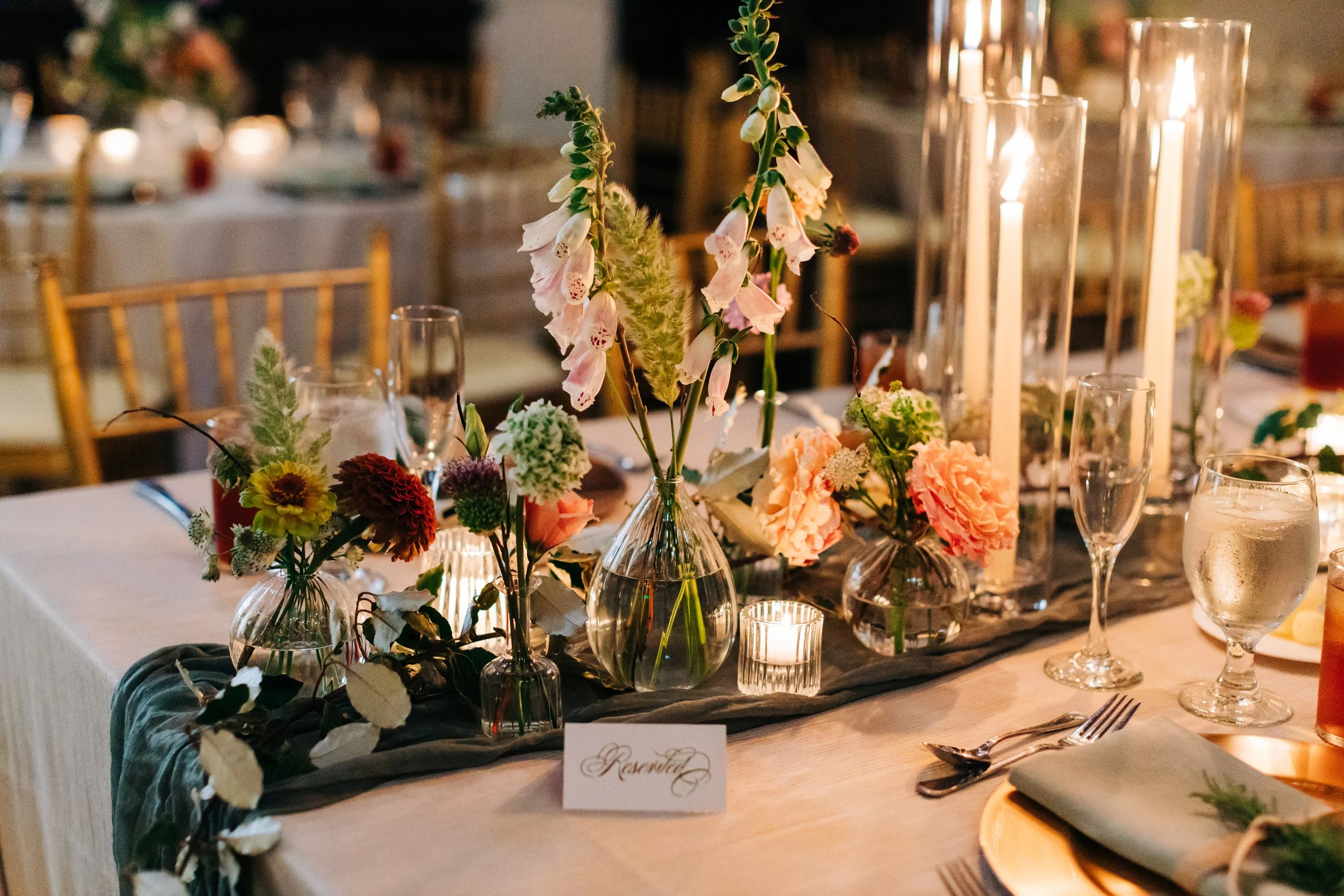Elegant wedding reception table with floral centerpiece, candles, and reserved sign.