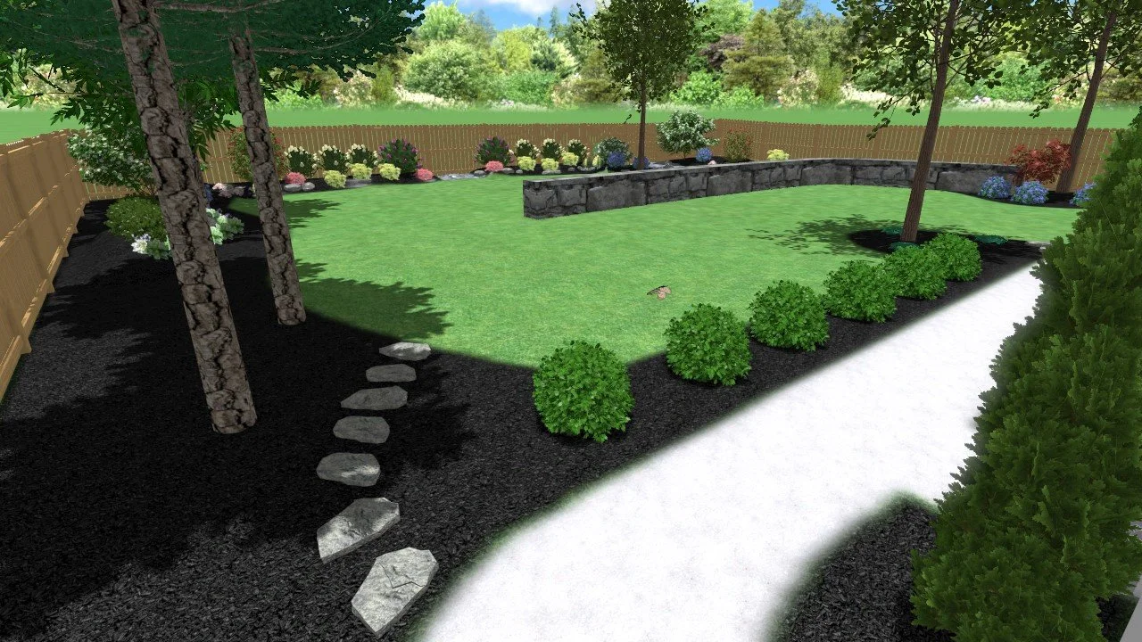 A landscaped backyard with a curved white pathway, green bushes, trees, colorful flower beds, a stone retaining wall, and a wooden fence in the background.