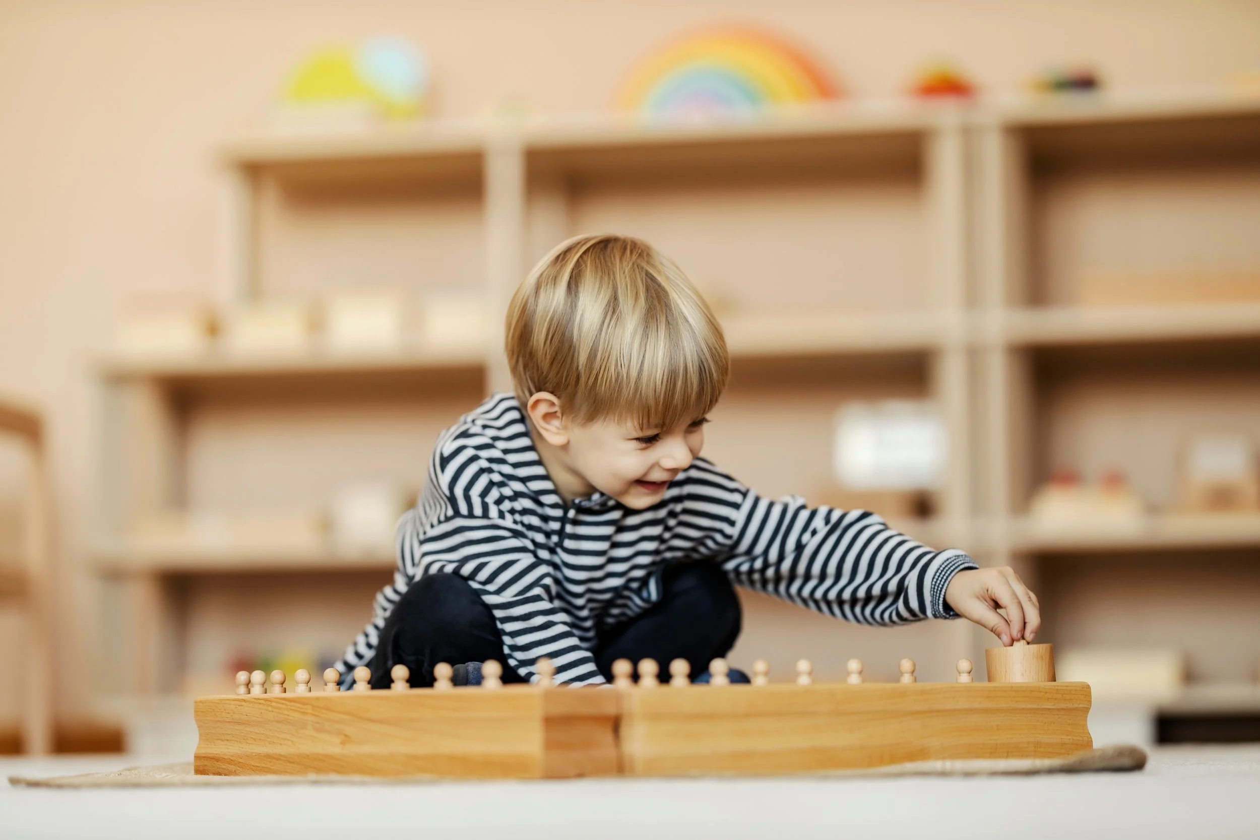 Young child playing with wooden peg game indoors, smiling and engaged.