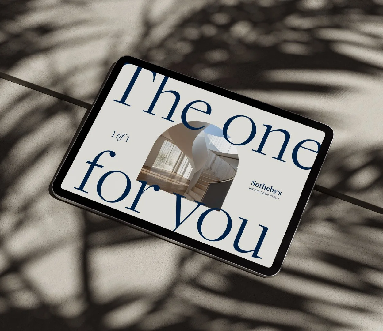 Tablet displaying Sotheby's real estate auction details, showing the phrase 'The one for you' and a photo of a staircase and windows inside a house.