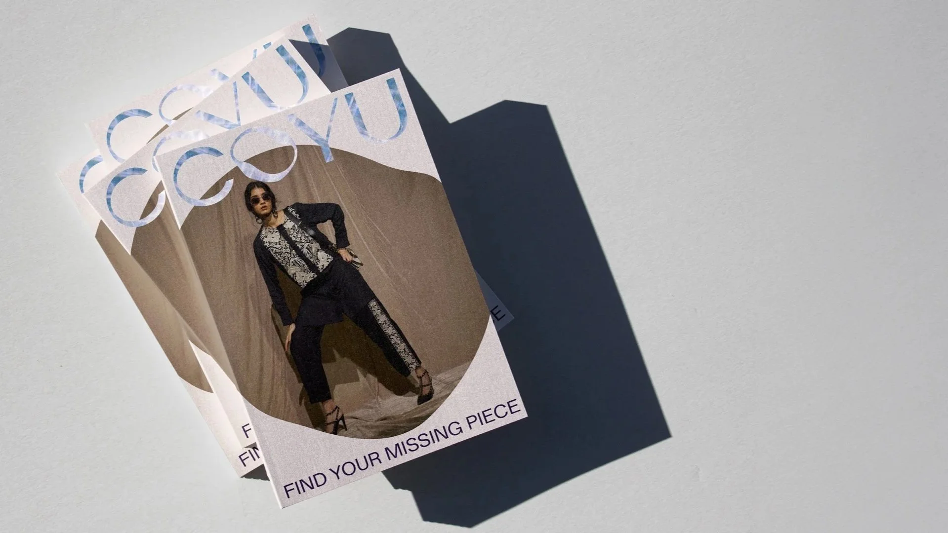 Fashion magazine with a woman in black and white clothing and sunglasses on a wooden background, with the caption "FIND YOUR MISSING PIECE"