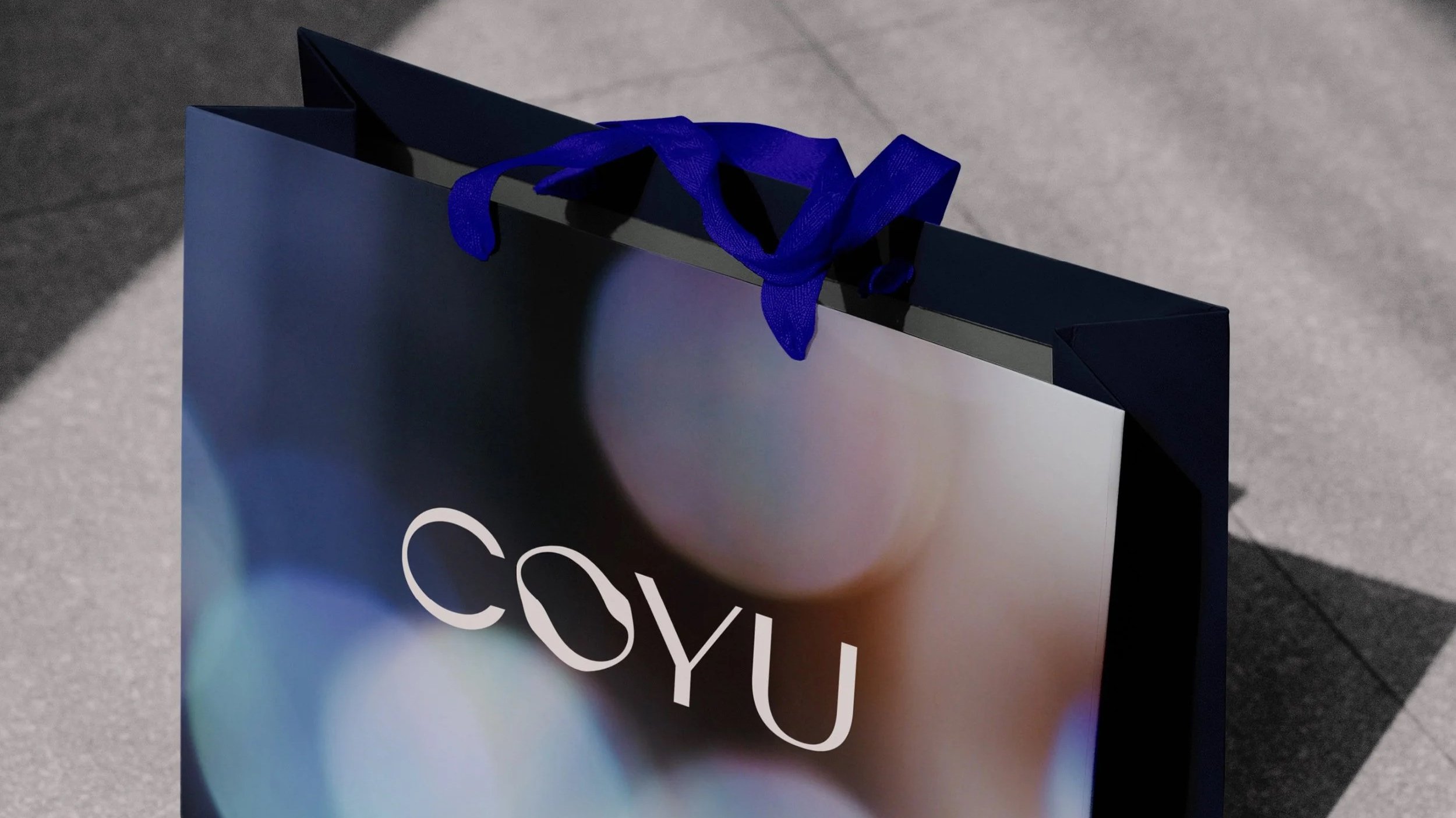A dark blue shopping bag with a purple ribbon handle on a tiled floor.