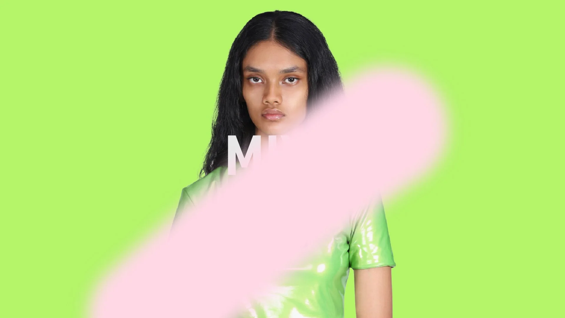 A woman with long black hair wearing a shiny green top with a pink smudge across the middle of the image, obscuring part of her face, and the letters 'M' and 'E' visible near her neck against a bright green background.