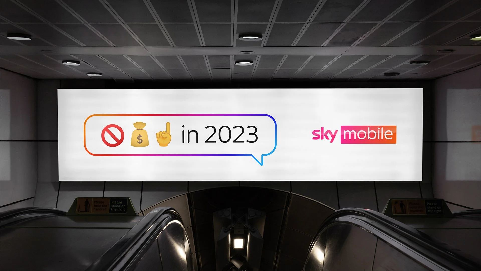 Advertisement for Sky Mobile with the text 'No money, No problem in 2023' with emoji icons, including a prohibition sign, a money bag, and a pointing finger, displayed on a large screen in an underground station.