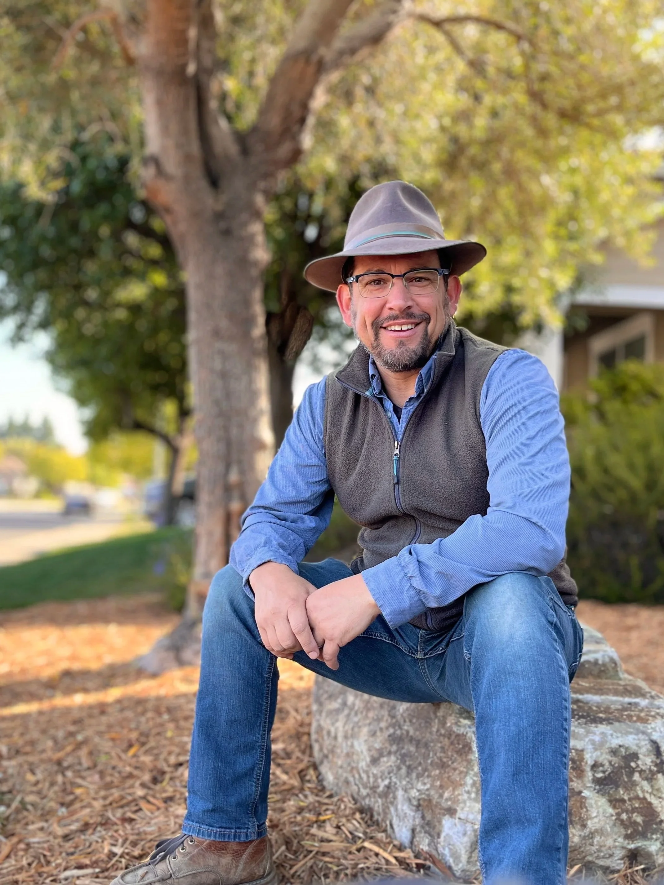 image of Stephen, a man in his middle age with goatee and glasses.  Wearing blue jeans, a button up blue shirt with a grey fleece vest over the top.