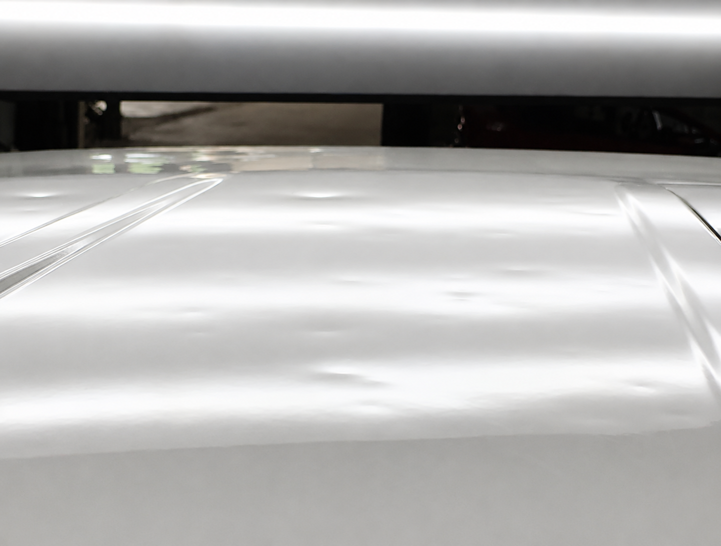 Close-up of a shiny, metallic object with reflective surfaces, possibly a vehicle or machinery, with a dark background.