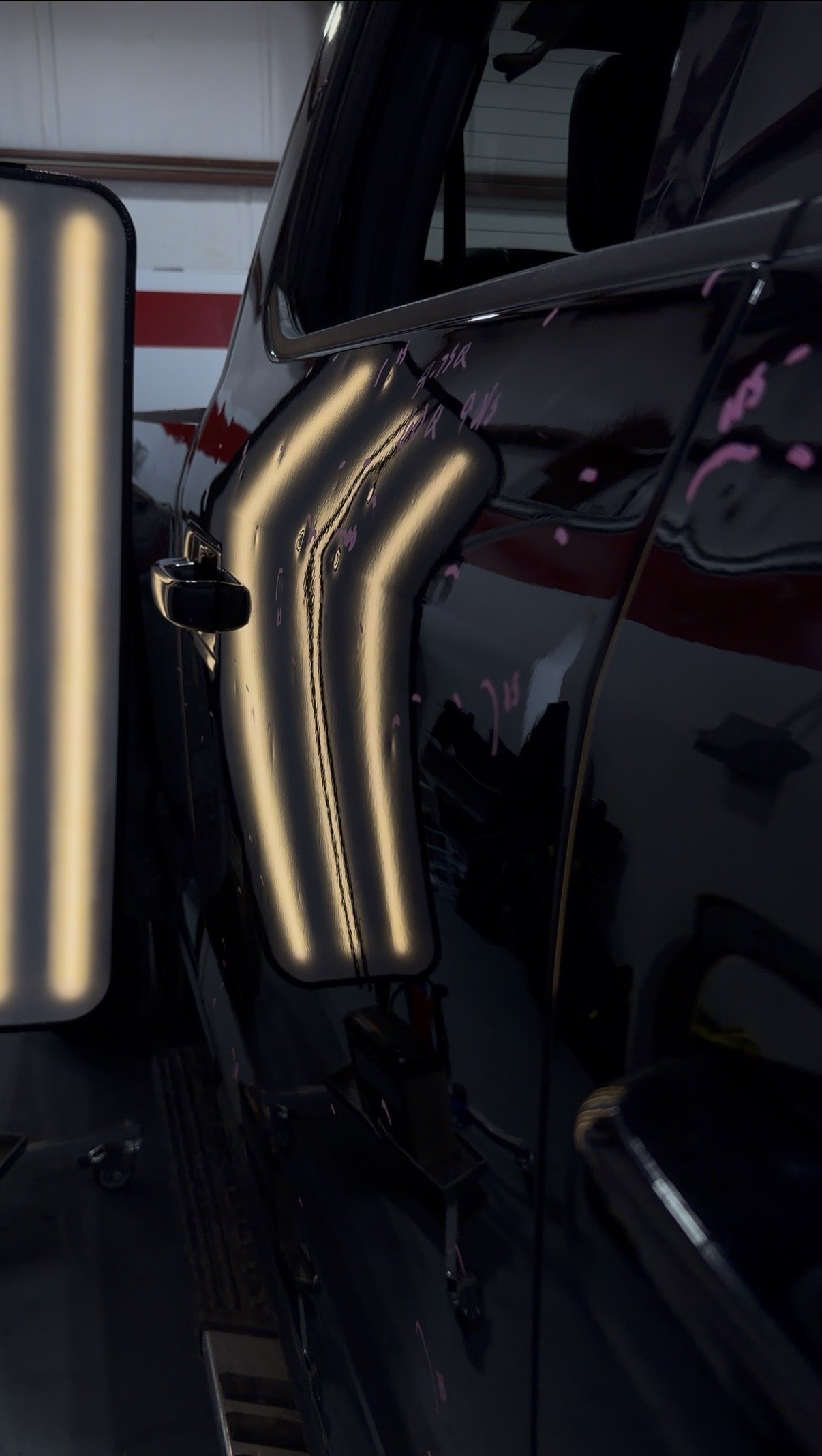 Close-up of a black vehicle's side mirror and door with reflections of the surroundings.