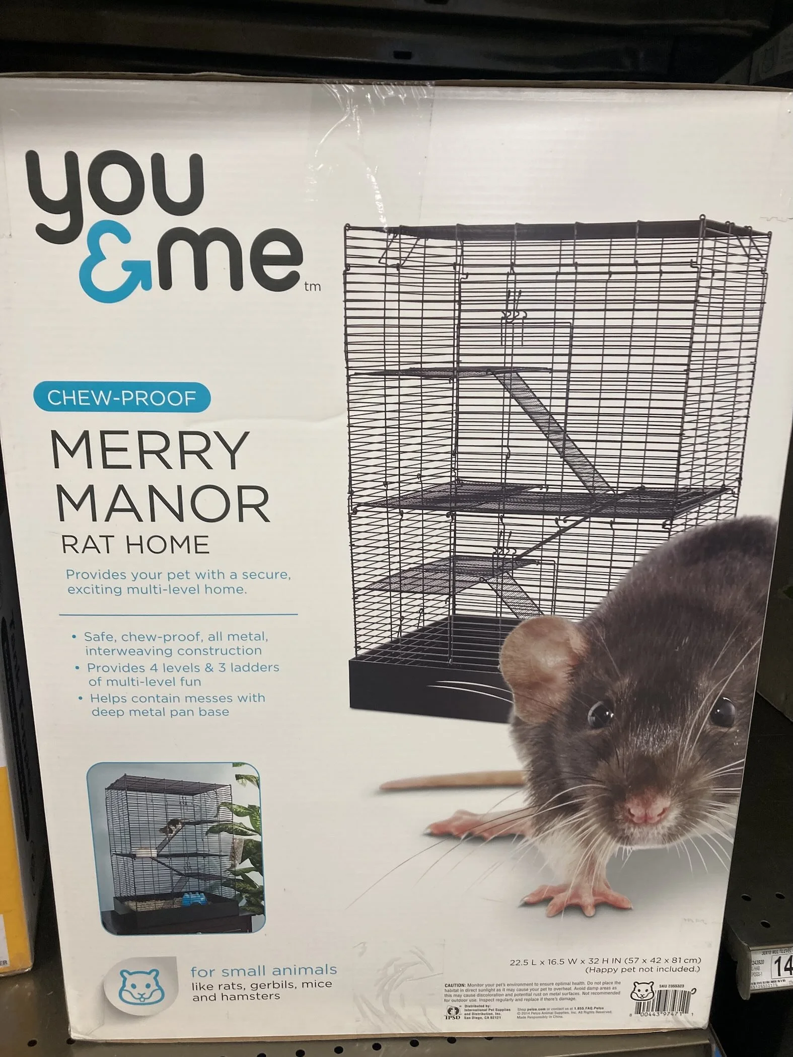 Packaging box for a small animal cage called 'Merry Manor Rat Home' by You & Me. The box features an image of a metal multi-level rat cage with ramps, and a picture of a black rat with pink paws and nose. The box indicates it's chew-proof, safe for small animals like rats, gerbils, mice, and hamsters, and provides specifications and features.