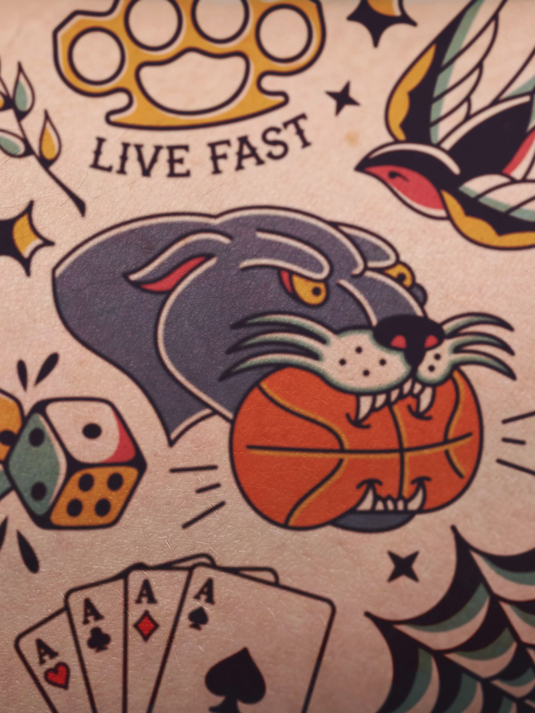 Tattoo of a panther biting into a basketball surrounded my other tattoos in an American traditional style.