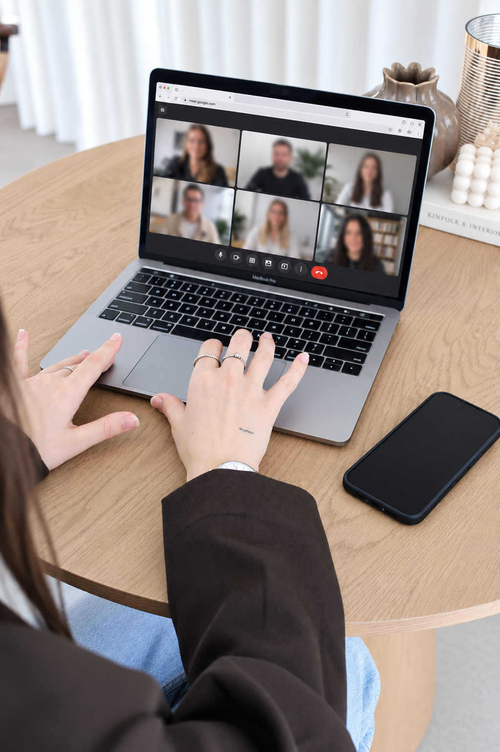Mains sur le clavier d'un MacBook Pro pendant un appel vidéo Google Meet avec six participants affichés à l'écran.