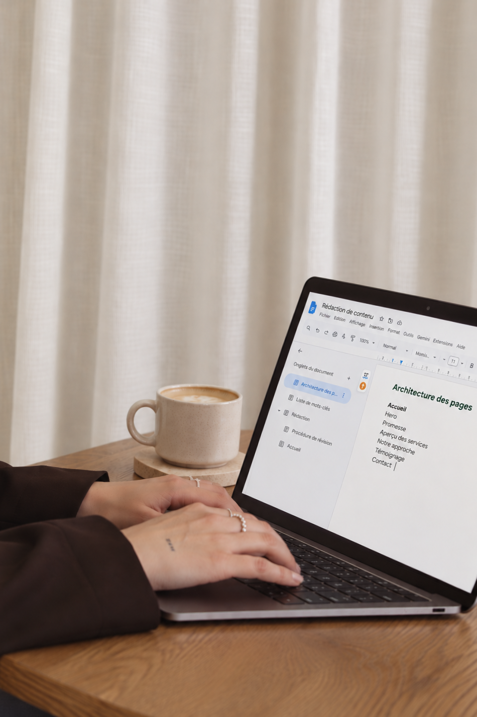 Abbie Richer rédige l'architecture des pages d'un site web dans Google Docs, sur son portable, avec un café latté