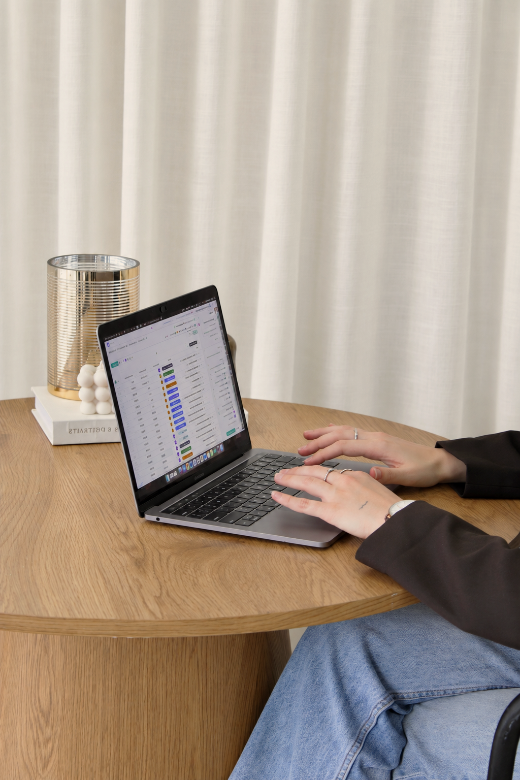 Abbie Richer gère les projets de ses clients québécois en marketing numérique  dans ClickUp sur son MacBook, assise à une table ronde en bois