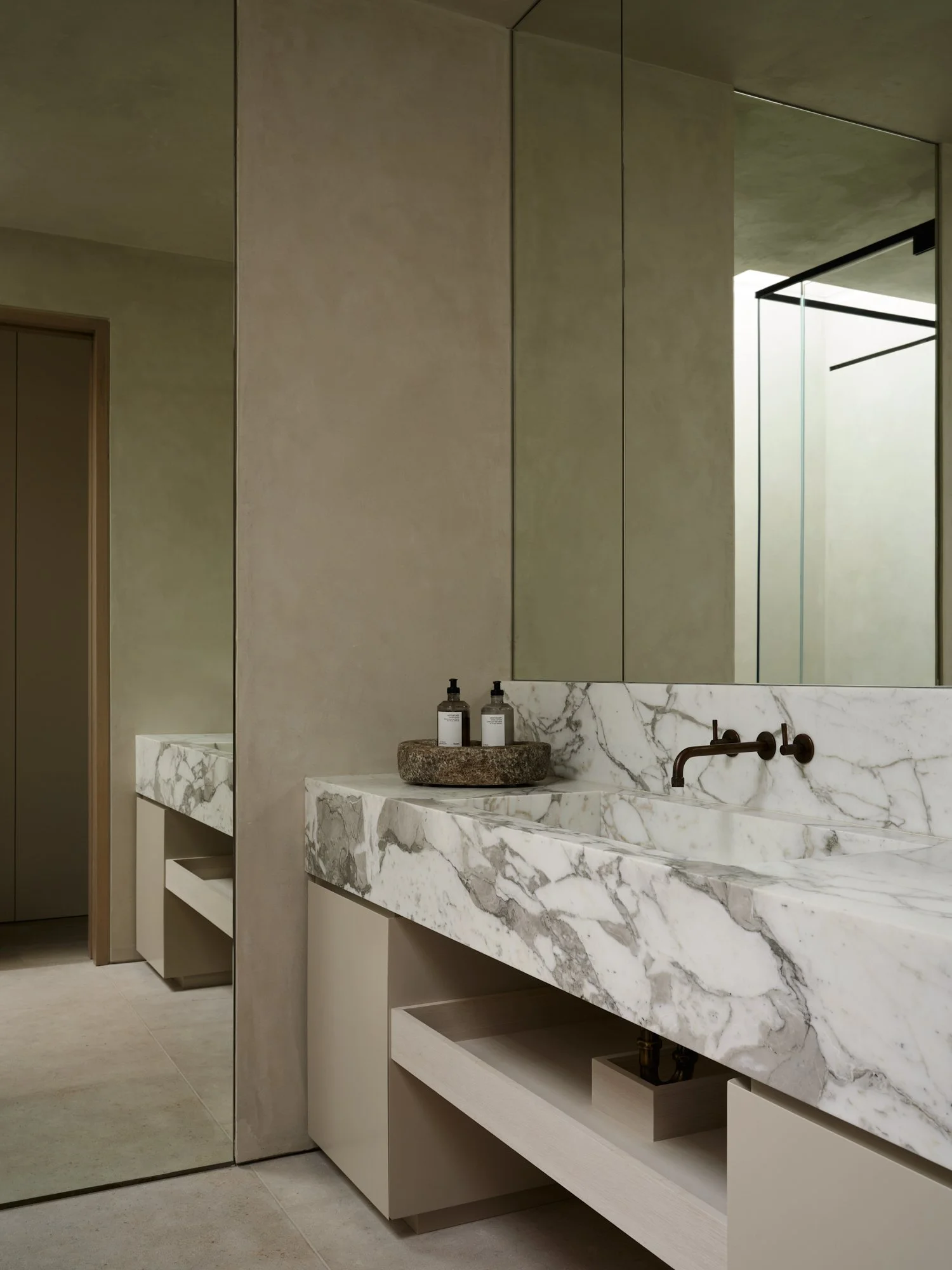Modern bathroom with a marble countertop, black faucet, large mirror, and minimal decor.