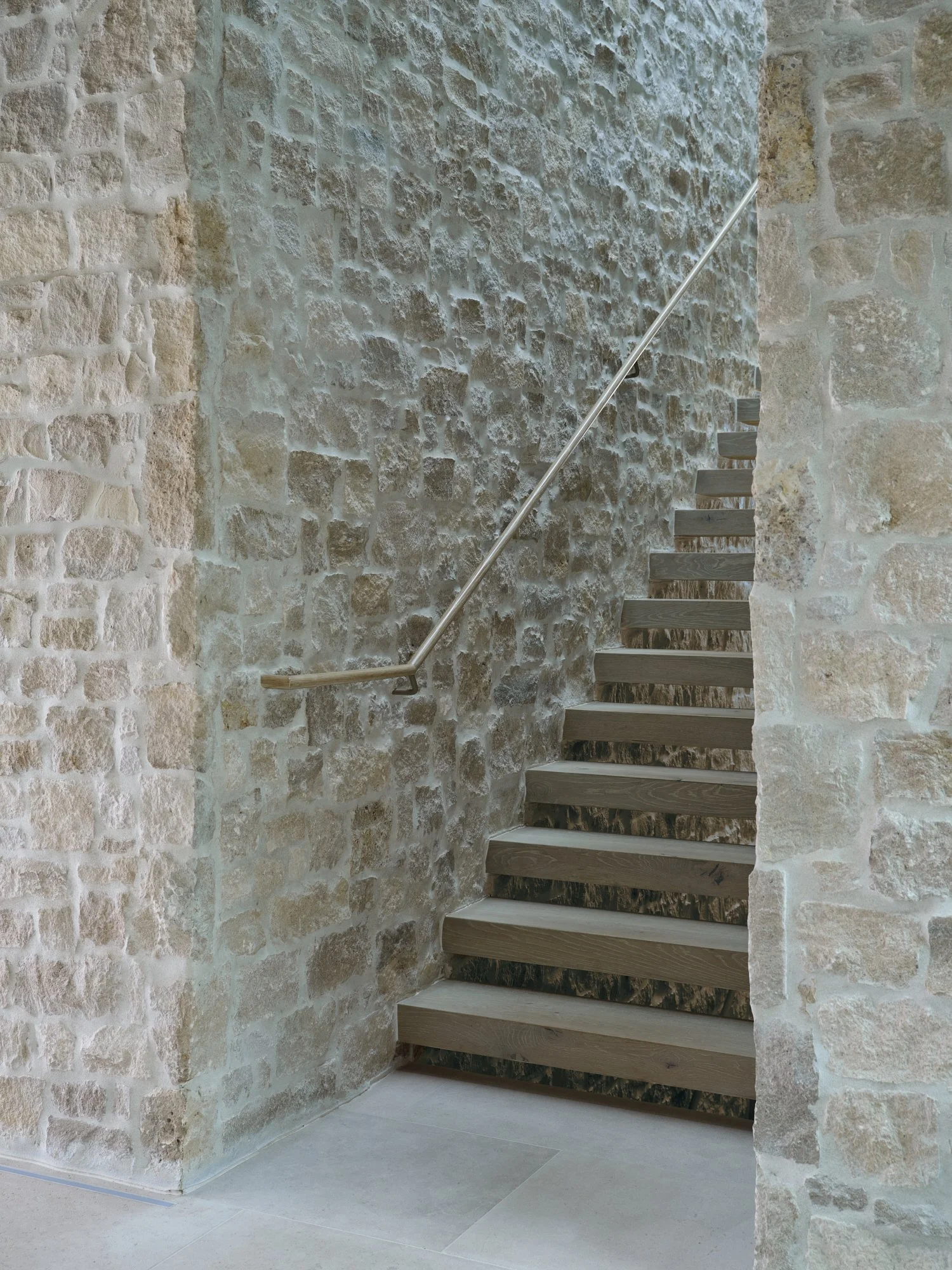 Stone interior wall with stairs and metal railing near a corner.