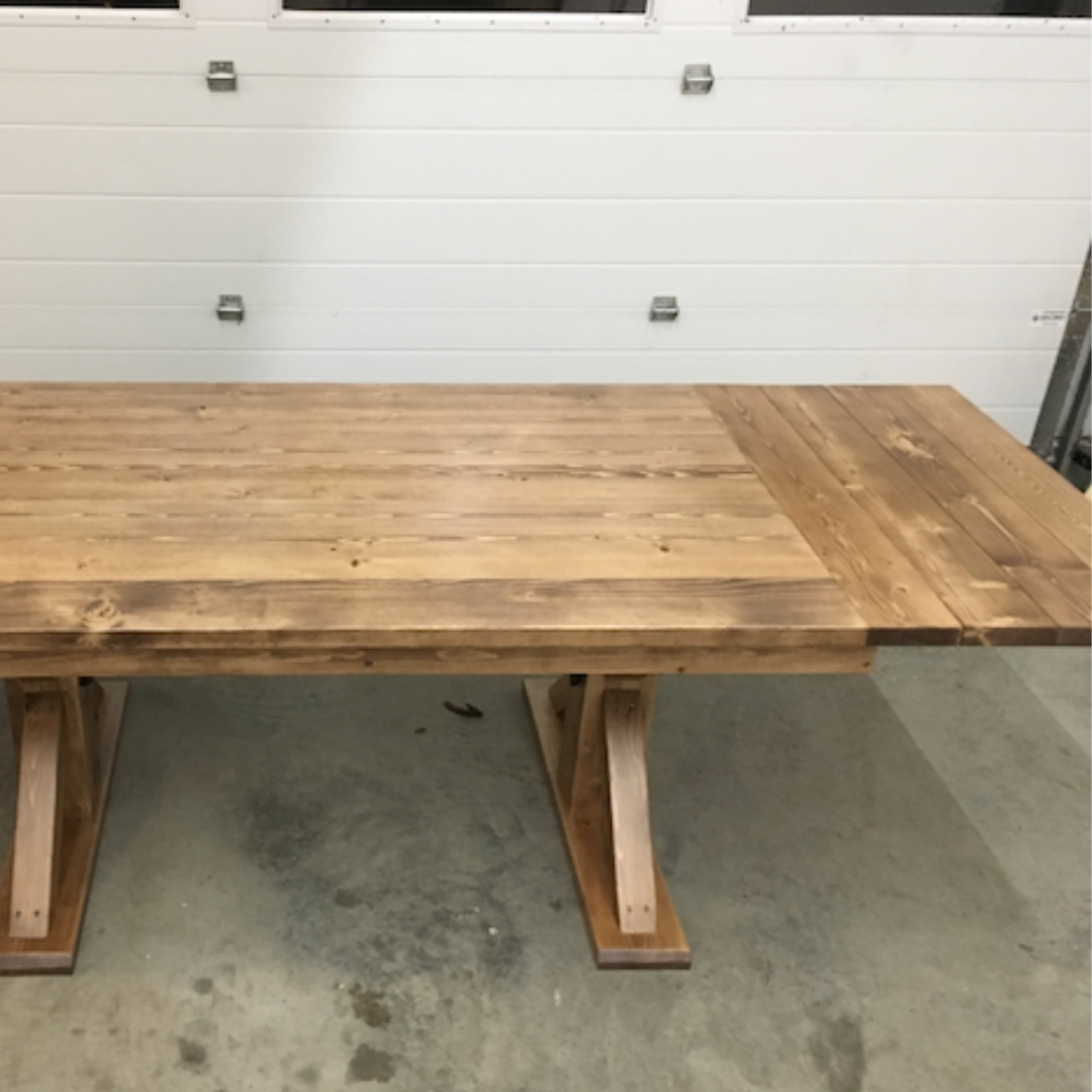 A wooden dining table with a visible extension added to its length.