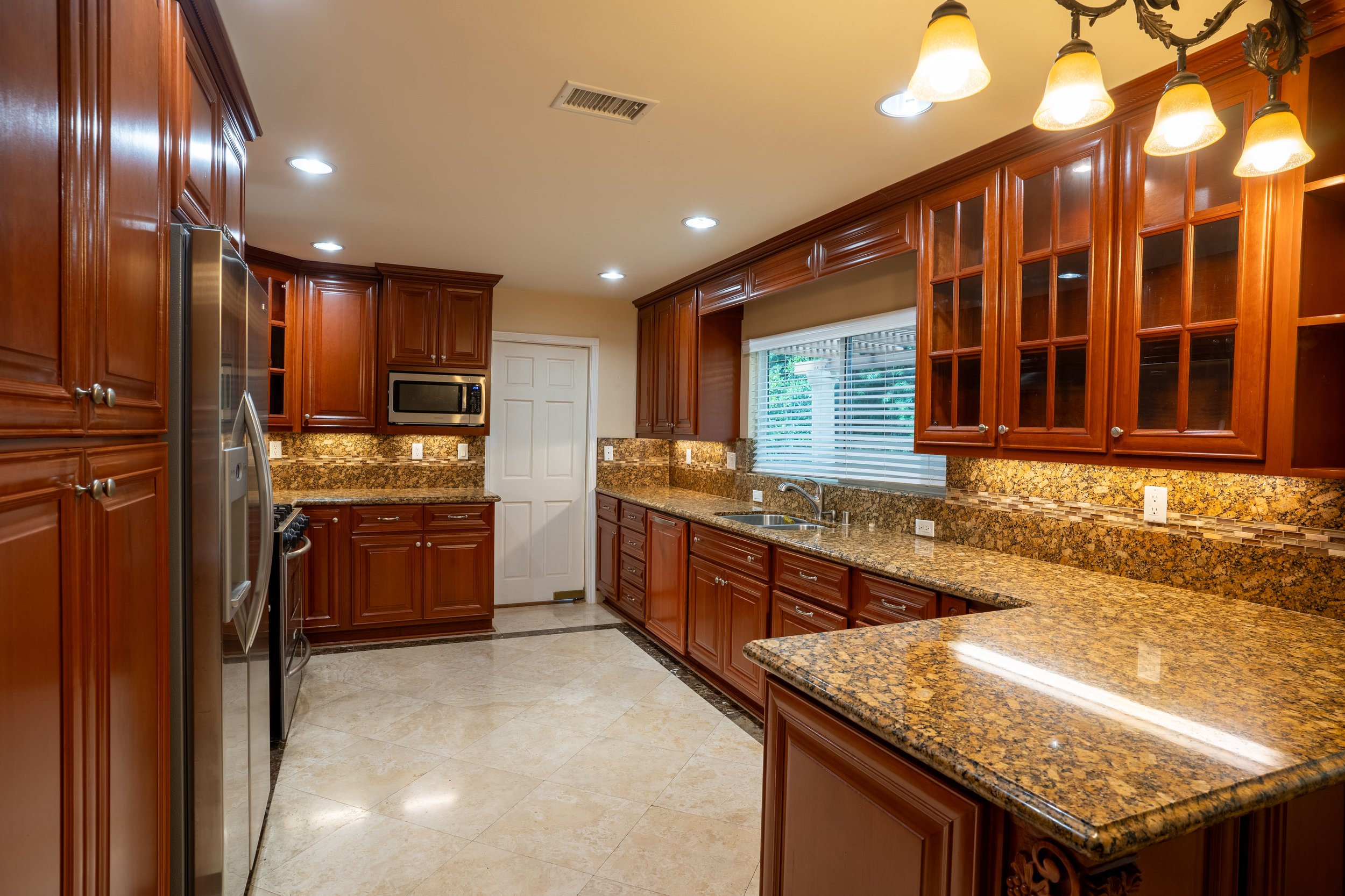 Kitchen with wooden cabinets, granite countertops, a window above the sink, and stainless steel appliances.