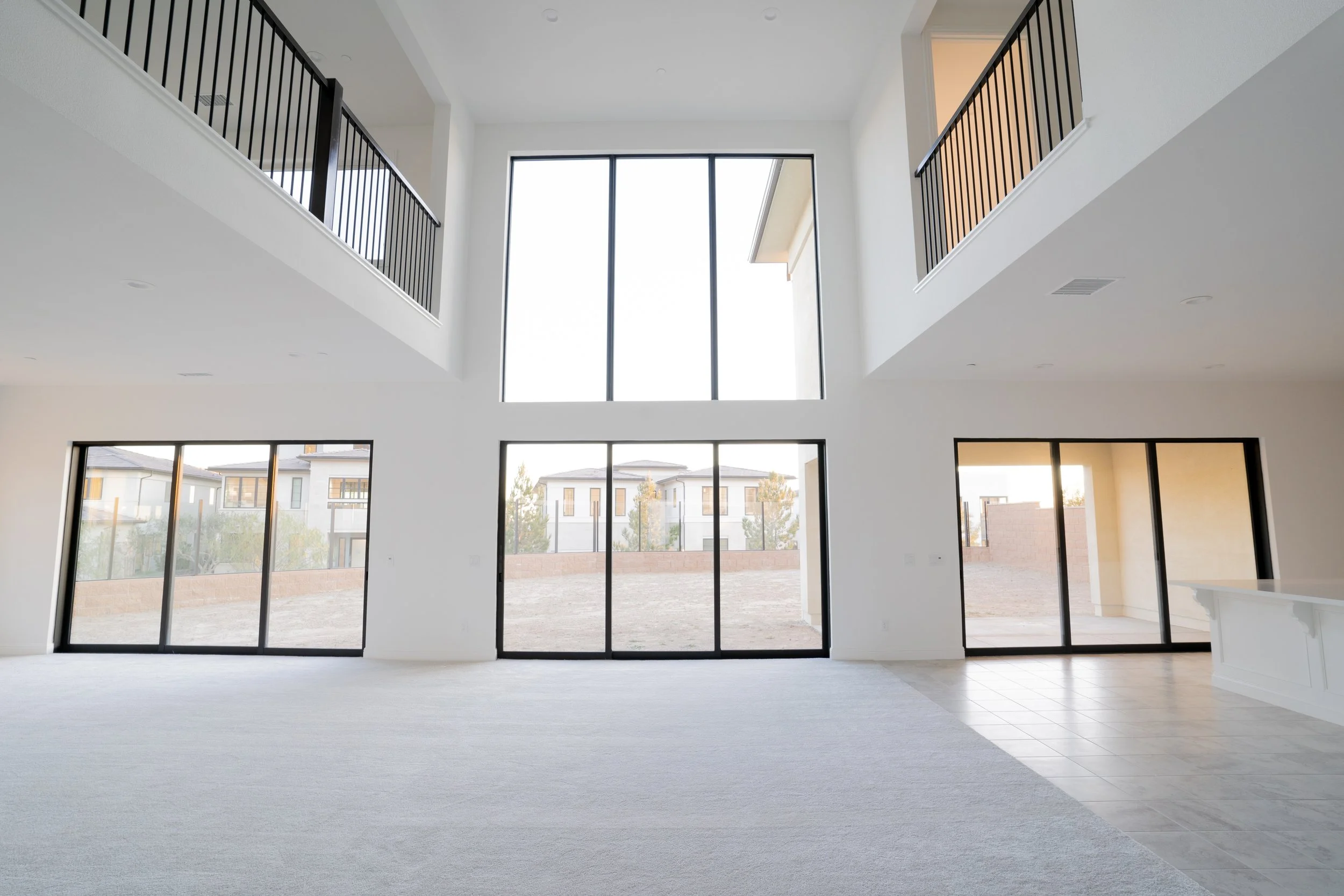Empty modern living room with large floor-to-ceiling windows and high ceiling