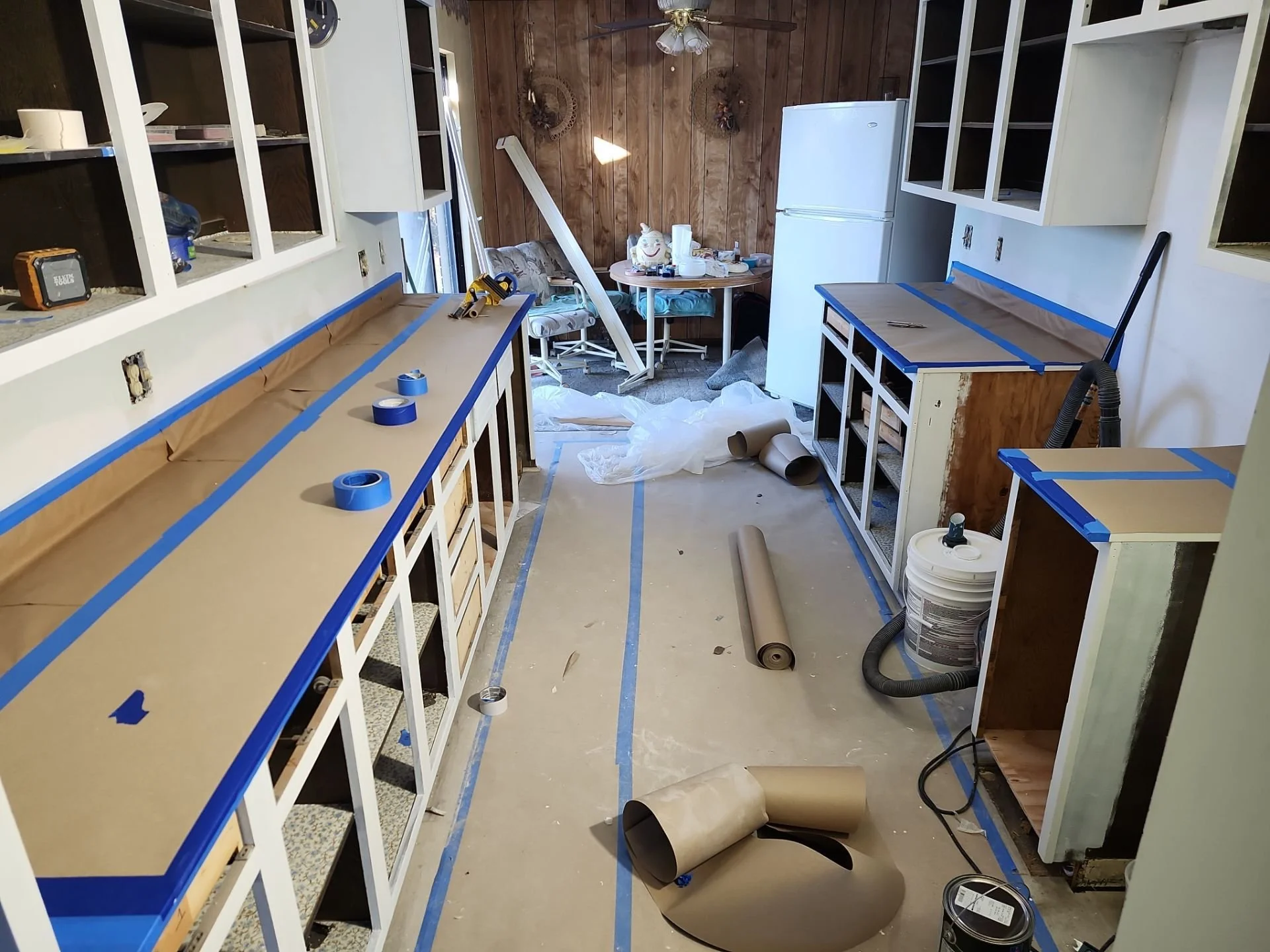 A kitchen under renovation with partially installed cabinets, tools, and construction materials scattered around.