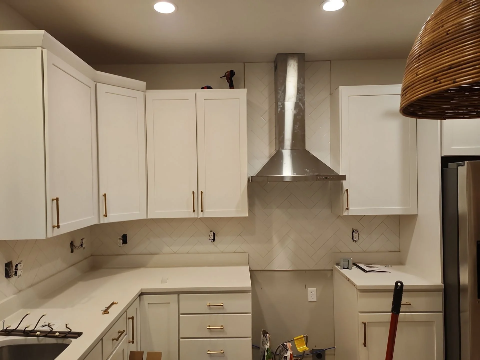 Kitchen with white cabinets, a stainless steel range hood, and other construction or renovation tools visible.