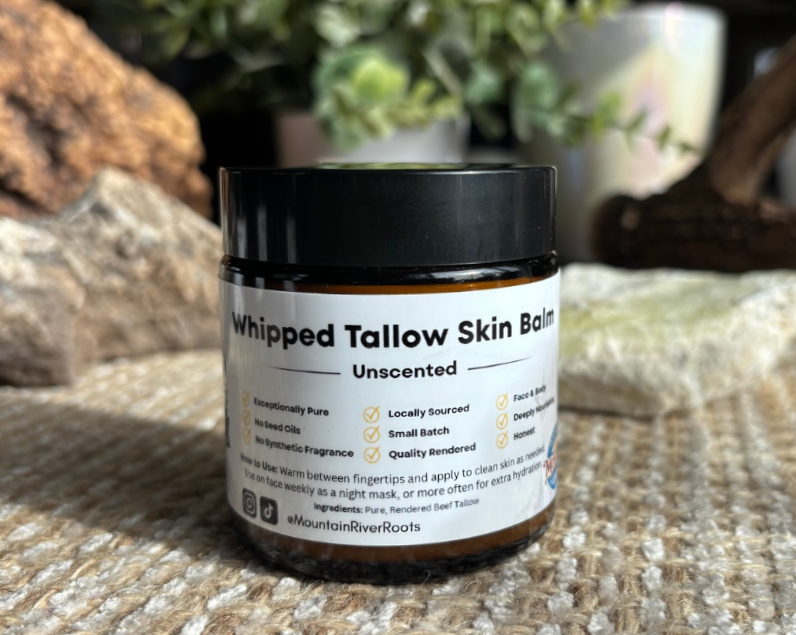 Modern wooden building with large glass window set in a mountainous landscape with sparse grassy vegetation.