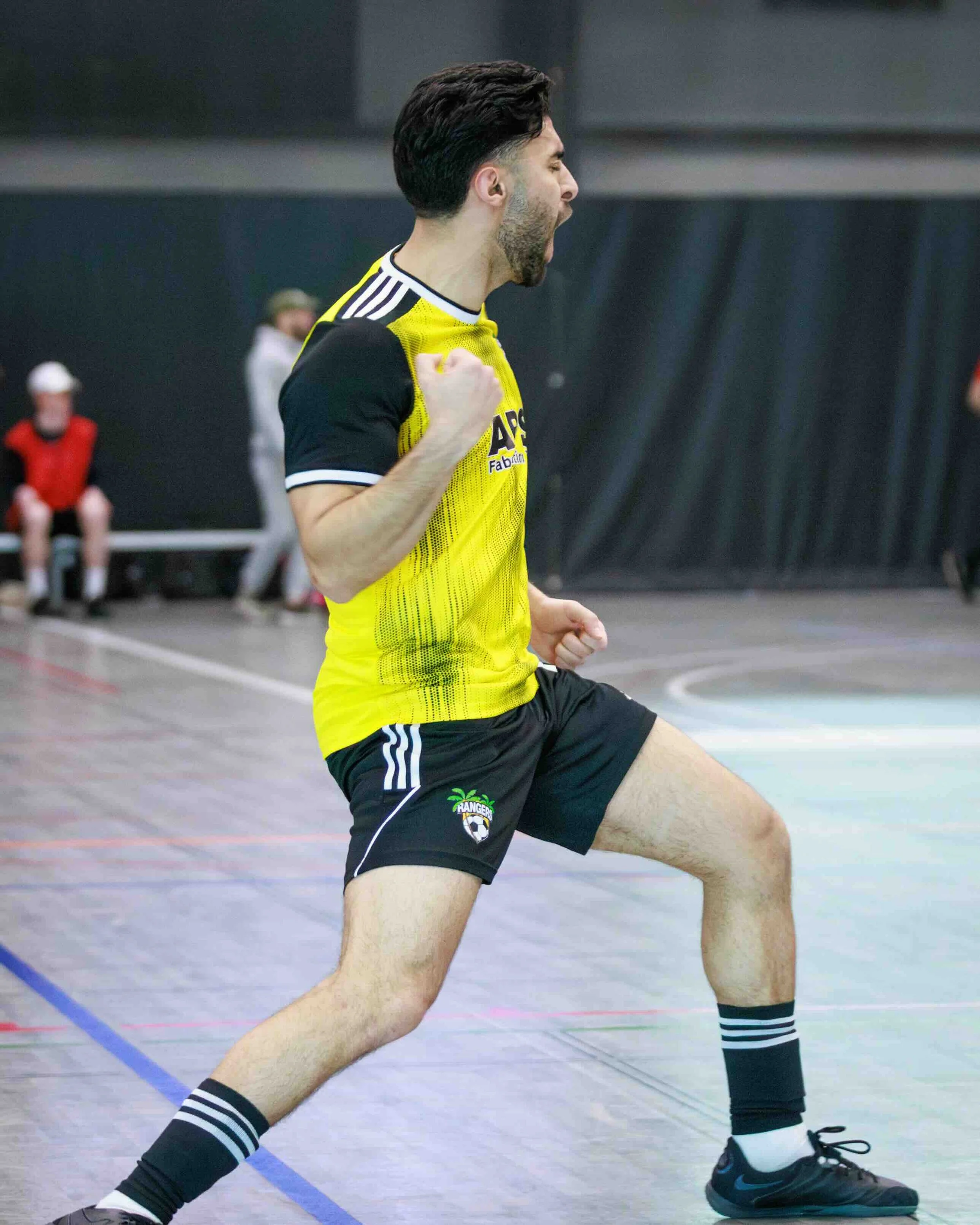 A man in a yellow and black sports uniform celebrating on an indoor sports court.