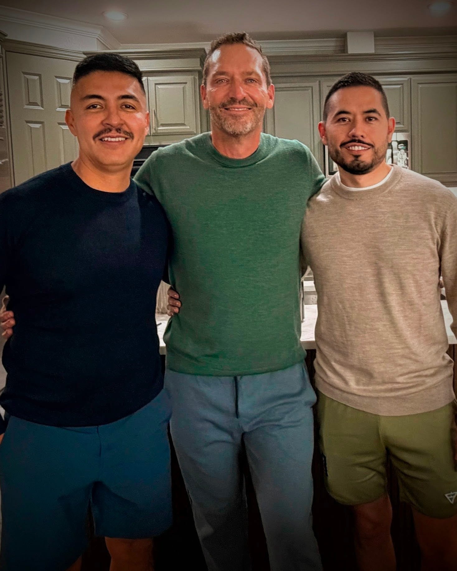 John Broady, a PCC-certified leadership coach, posing warmly with his two partners in a bright, modern setting.