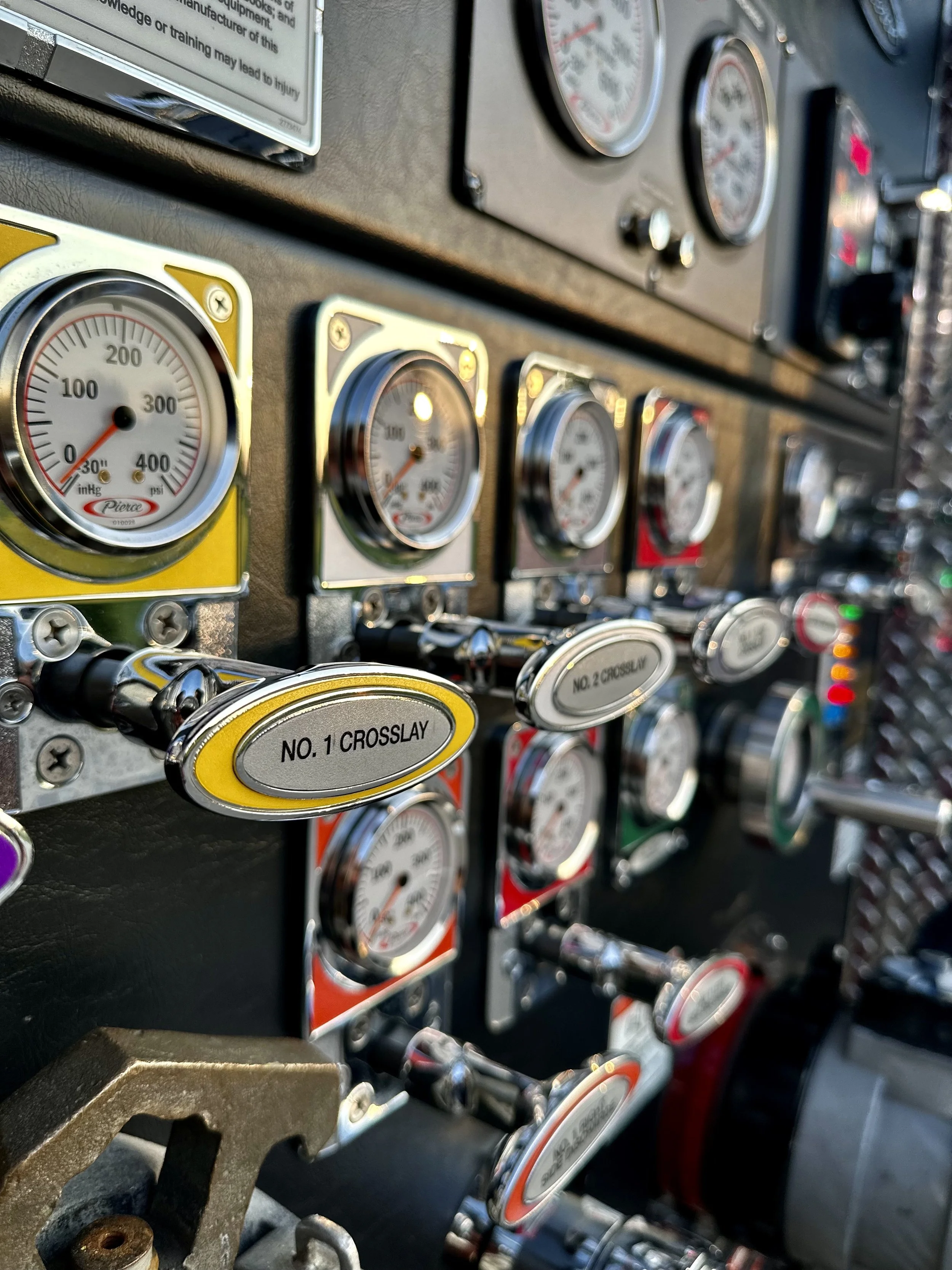 Close-up of a control panel with multiple pressure and gauge meters, labeled switches including 'No. 1 Crosslay' and 'No. 2 Crosslay', with various colorful buttons and dials.