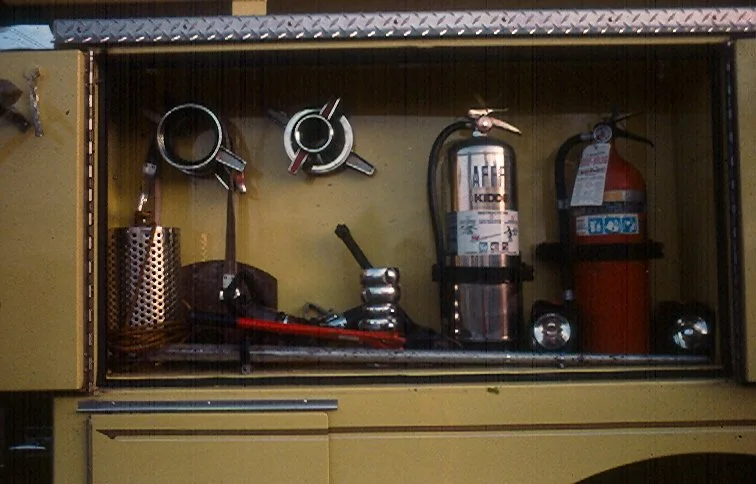 Fire extinguisher and fire suppression system inside a yellow metal cabinet with hoses and gauges.
