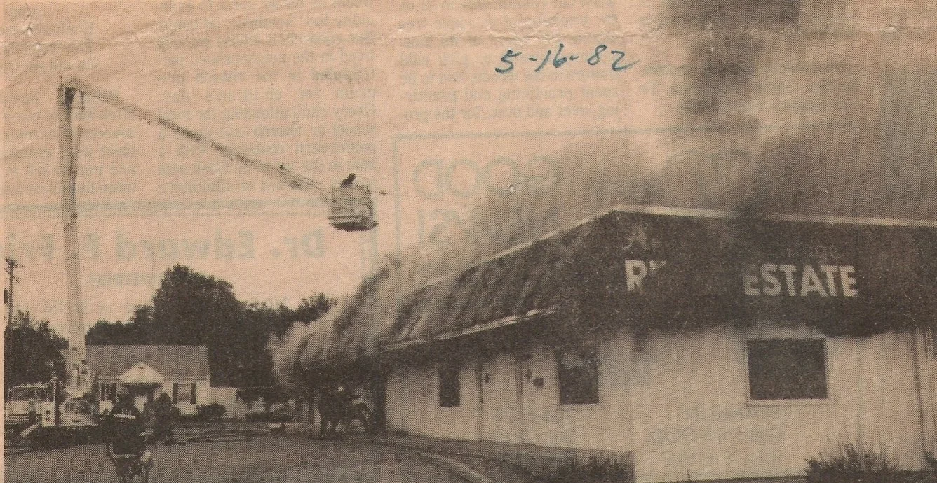 A burning building labeled 'RESTAURANT' with smoke coming from it, a crane overhead, and a person riding a bicycle in the foreground. Handwritten date '5-16-82' at the top.