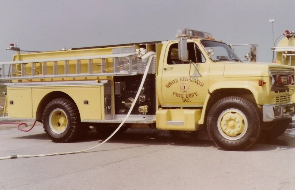Yellow fire truck with hoses attached, labeled 'White River Valley Fire Dept. Inc.' parked on an outdoor surface