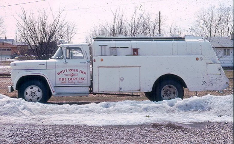 An old white fire department truck from White River Township, parked on snow-covered ground with a rural background.
