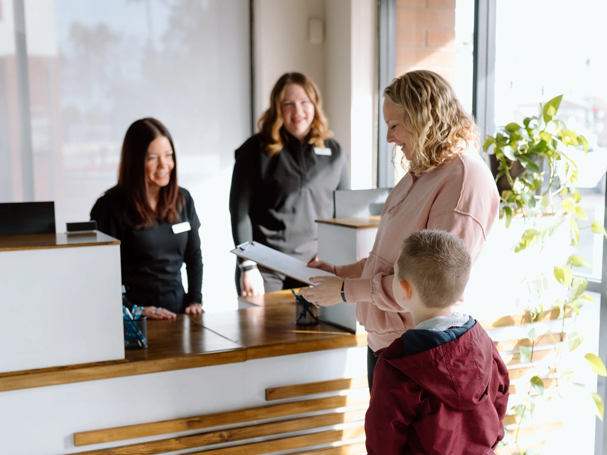 Couple with newborn baby at front desk in neurologically-based chiropractic office in Gilbert, Arizona