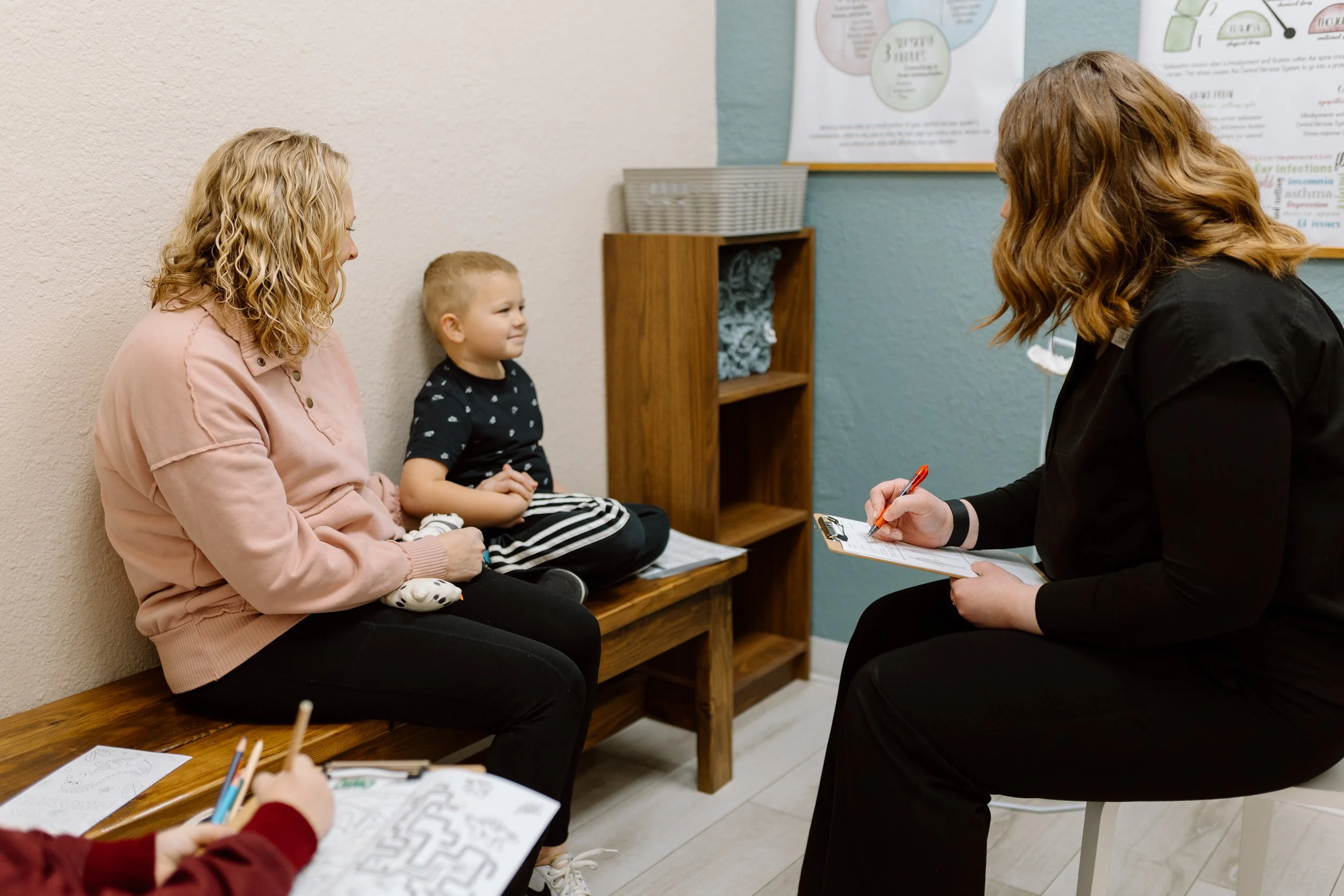 Chiropractic staff member reviews paperwork of family in neurologically-based chiropractic office in Gilbert, Arizona