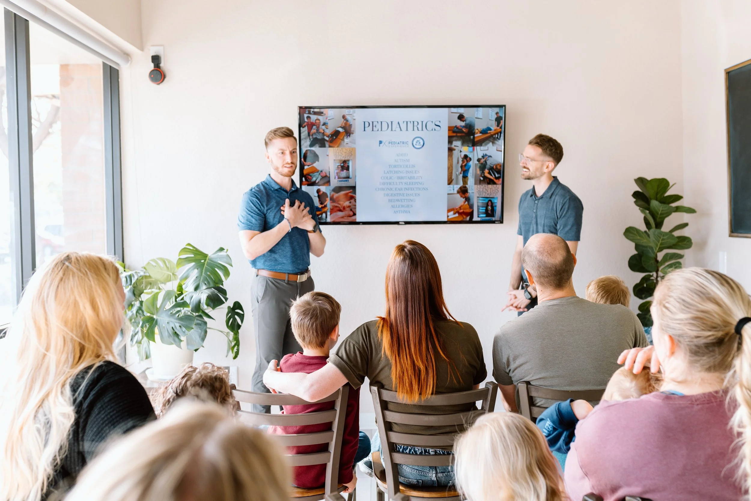 Mother and father look at their newborn baby swaddled in a blanket in neurologically-based chiropractic office in Gilbert, Arizona.