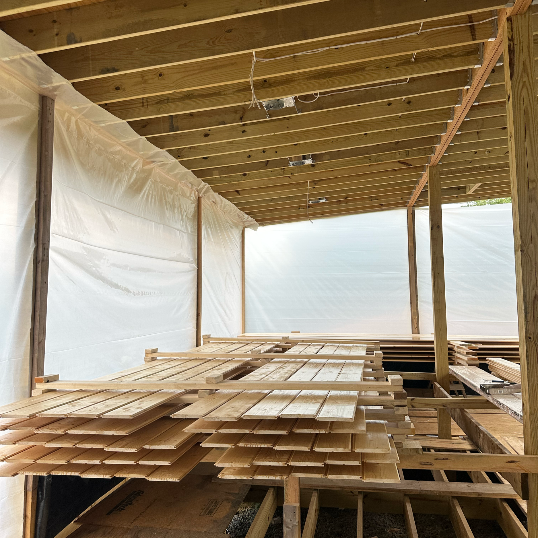 Construction workers renovating a building, with one worker climbing a ladder and another worker in the background, surrounded by construction debris and scaffolding.