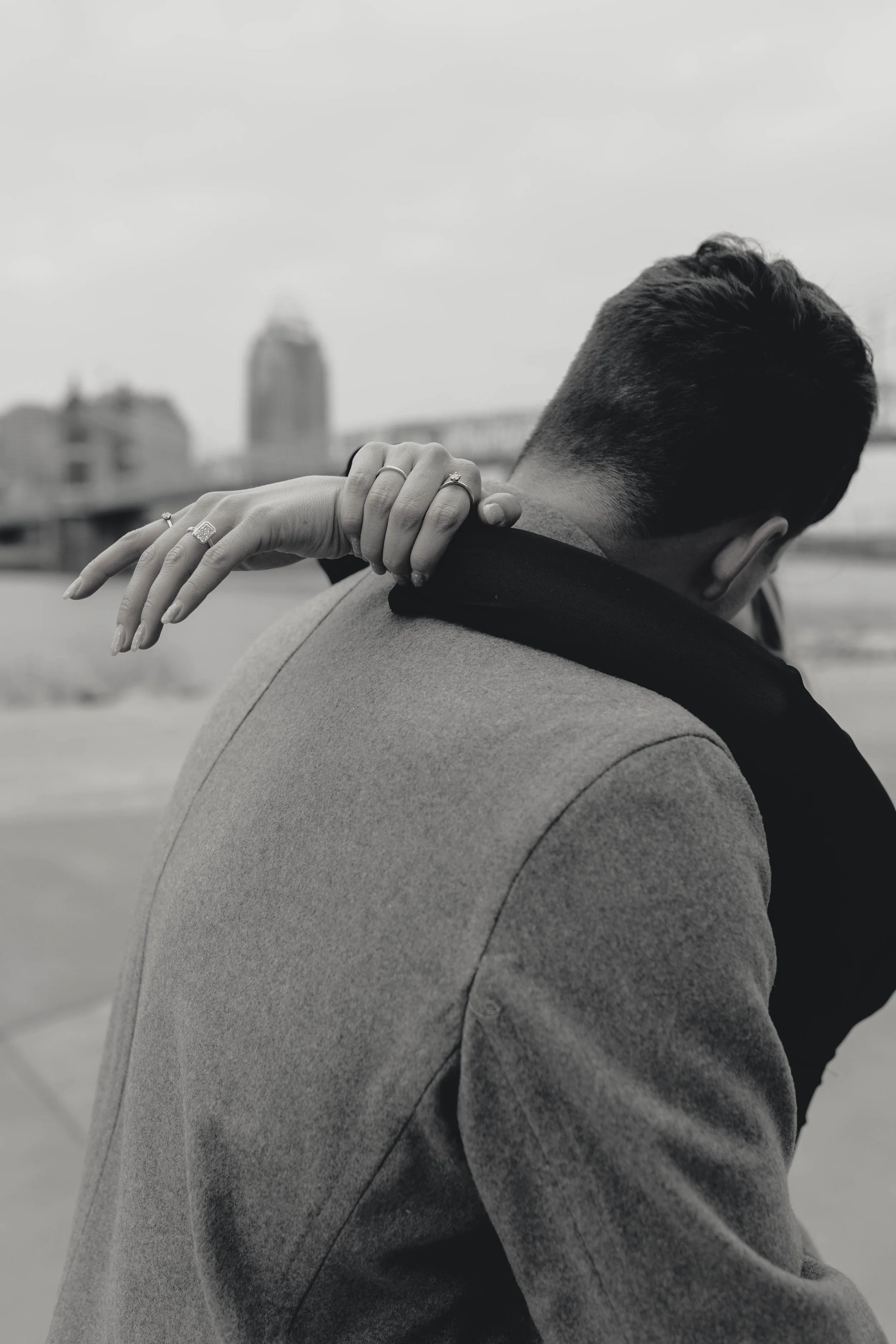 couple getting engaged at covington riverwalk with cincinnati skyline in background